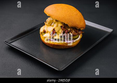 Délicieux burger avec de la viande déchirée sur un plateau noir Banque D'Images