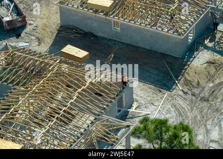 Constructeurs travaillant sur la construction de toit de maison résidentielle inachevée avec structure de cadre en bois dans la région suburbaine de Floride. Développement du logement Banque D'Images