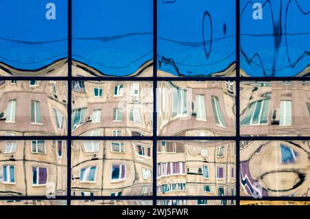 Reflet tordu de maisons dans une fenêtre en verre Banque D'Images