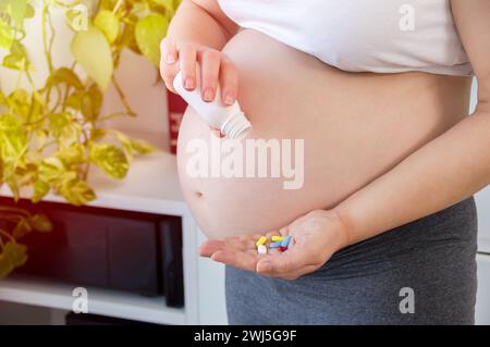 Plan recadré d'une femme enceinte méconnaissable prenant des médicaments à la maison Banque D'Images