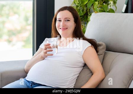 Plan d'une femme buvant de l'eau alors qu'elle était preganante à la maison Banque D'Images