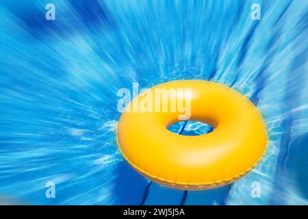 Tube intérieur jaune gonflable flottant dans des eaux bleues claires avec effet de flou de mouvement Banque D'Images