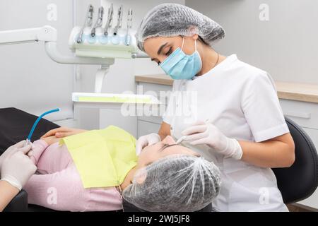 Chirurgien dentiste professionnel et assistant effectuant l'opération dentaire dans une clinique avec l'équipement moderne Banque D'Images