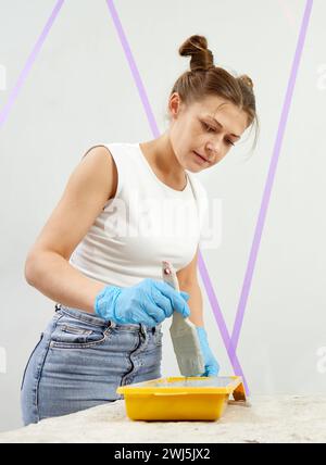 Jeune femme avec peinture pinceau mur de peinture dans une nouvelle maison. Concept de décoration d'intérieur Banque D'Images