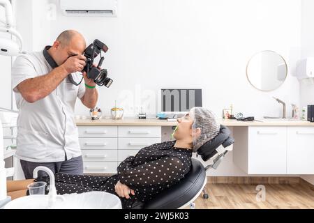 Dentiste photographiant les dents du patient à des fins de dossier médical avant et après la chirurgie dans le cabinet du dentiste Banque D'Images