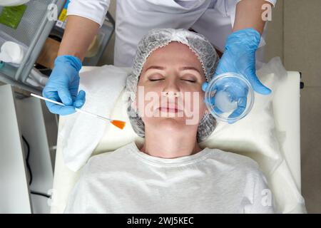 Cosmétologue applique de l'huile sur le visage du client dans le salon de beauté Banque D'Images