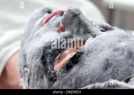 Jeune femme avec un masque à bulles d'oxygène noir sur son visage dans un salon de beauté Banque D'Images