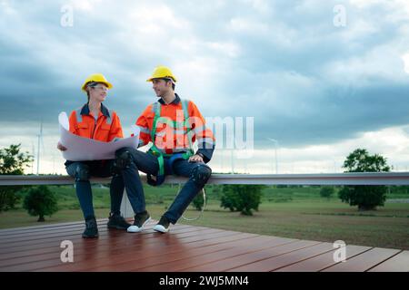 Ingénieur et technicien discutant du plan sur le site de construction avec fond d'éolienne Banque D'Images