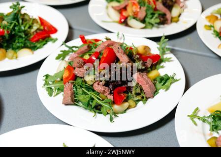 Salade de bœuf frais avec légumes sur assiette. Une salade de bœuf saine avec roquette, poivrons rouges et légumes verts mélangés, servie dans une assiette blanche. Banque D'Images