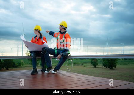 Ingénieur et technicien discutant du plan sur le site de construction avec fond d'éolienne Banque D'Images