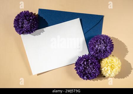 Belles petites fleurs violettes sur enveloppe bleue postale sur fond beige, espace de copie de note de papier vide pour le texte, printemps, carte de voeux pour les vacances. Concept de livraison de fleurs Banque D'Images