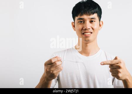 L'homme asiatique se brosse les dents le matin, tient une brosse à dents, sourit et pointe Banque D'Images