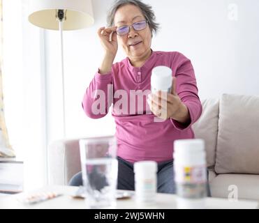 Femme âgée lisant le contenu d'une boîte de médicaments à la maison Banque D'Images