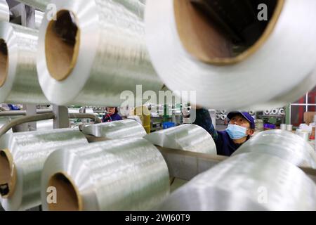 CHONGQING, CHINE - 11 FÉVRIER 2024 - Une travailleuse inspecte une chaîne de production automatisée dans l'atelier de production d'une entreprise de fibres de verre en CH Banque D'Images