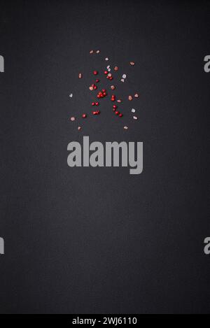 Table en béton noir avec poivre rose épicé et sel de l'Himalaya. Peut être utilisé comme arrière-plan Banque D'Images