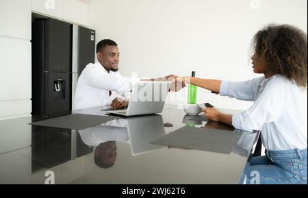 Les deux jeunes entreprises boivent du vin et utilisent leurs ordinateurs portables pour partager des informations les uns avec les autres dans leur salon de la maison. Banque D'Images