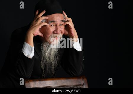 Portrait d'un vieil homme au visage ridé avec une longue barbe blanche sur fond noir, prise en studio Banque D'Images