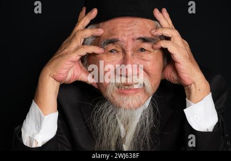 Portrait d'un vieil homme au visage ridé avec une longue barbe blanche sur fond noir, prise en studio Banque D'Images