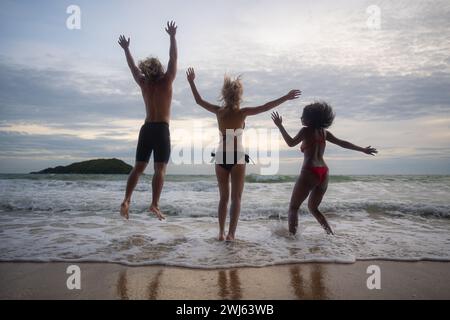 Groupe d'amis s'amusant sur la plage à l'heure du coucher du soleil. Banque D'Images