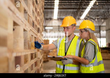 Les deux ouvriers travaillent dans une usine de menuiserie, vérifiant l'inventaire du bois dans l'entrepôt en bois Banque D'Images