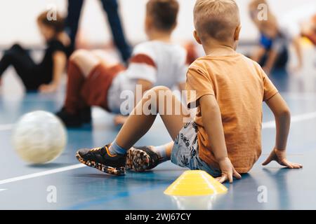 Enfants en classe d'éducation physique à l'école. Groupe de petits garçons rampant sur le terrain d'entraînement intérieur. Pratique de futsal de football en salle pour elementa Banque D'Images