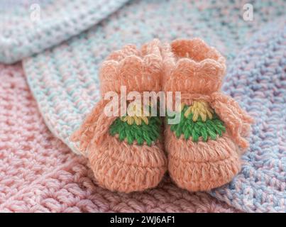 Chaussons bébé crochetés pêche sur des carrés tricotés Banque D'Images