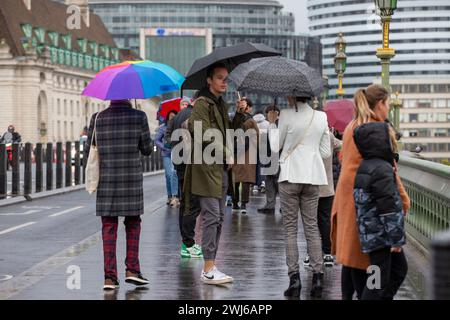 Londres, UK, 13th Feb 2024 touriste file d'attente sous la pluie avec des parapluies pour prendre des photos de l'emblématique boîte téléphonique rouge à Londres et profiter des sites à Londres malgré la pluie crédit : Richard Lincoln / Alamy Live News Banque D'Images