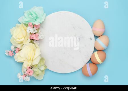 Cercle de marbre avec œufs en papier décorés et fleurs pastel sur fond bleu. Copier espace simple pastel fond rustique pour traditionnel holid de Pâques Banque D'Images
