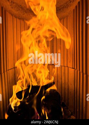 Une photographie en gros plan montrant un feu allumé à l'intérieur d'un poêle de cheminée, émettant des flammes et une lumière scintillante. Banque D'Images