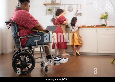 Une grande famille avec un père portant une jambe prothétique, ils font le petit déjeuner ensemble avec plaisir dans la salle de cuisine de th Banque D'Images