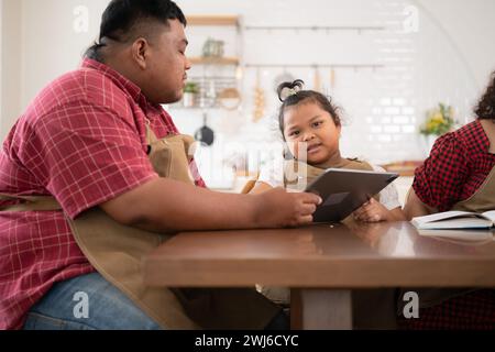 Une grande famille avec un père portant une prothèse de jambe, est heureux d'aider un enfant avec ses devoirs et de s'amuser ensemble Banque D'Images