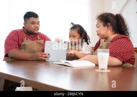 Une grande famille avec un père portant une prothèse de jambe, est heureux d'aider un enfant avec ses devoirs et de s'amuser ensemble Banque D'Images