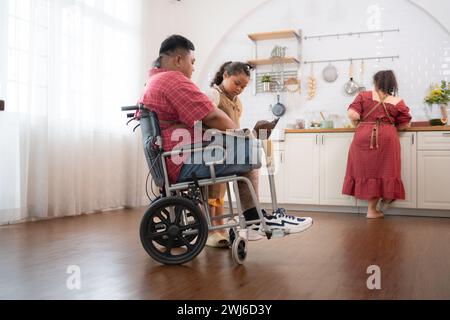 Une grande famille avec un père portant une jambe prothétique, ils font le petit déjeuner ensemble avec plaisir dans la salle de cuisine de th Banque D'Images