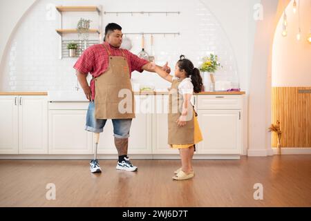 Une famille de grande taille avec un père portant une jambe prothétique, la fille s'est amusée à jouer avec son père avant d'aider à cuisiner. po Banque D'Images