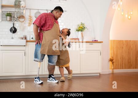 Une famille de grande taille avec un père portant une jambe prothétique, la fille s'est amusée à jouer avec son père avant d'aider à cuisiner. po Banque D'Images