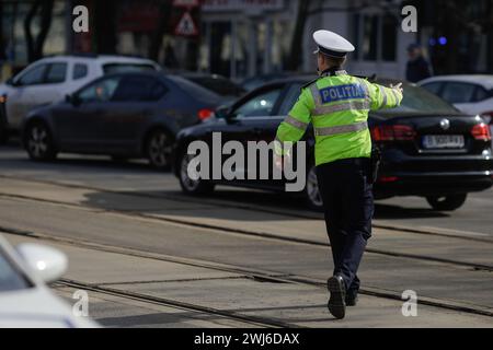 Bucarest, Roumanie - 13 février 2024 : agent de la police routière roumaine gère la circulation dans une rue animée. Banque D'Images