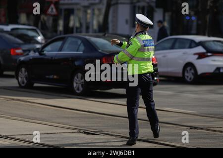 Bucarest, Roumanie - 13 février 2024 : agent de la police routière roumaine gère la circulation dans une rue animée. Banque D'Images