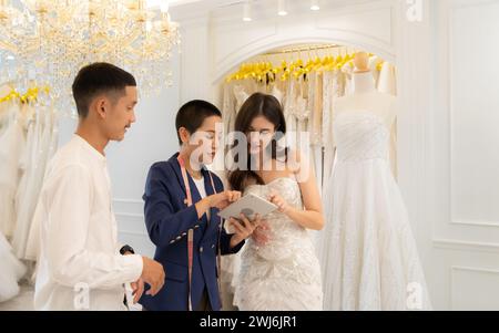 Les concepteurs et tailleurs de robe de mariée mesurent la taille de la robe contre la figure de la mariée quand elle vient à essayer la robe en o Banque D'Images