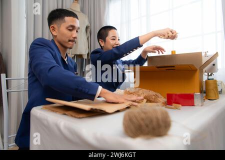Les vêtements de jeunes hommes d'affaires asiatiques et de femmes sont emballés pour la livraison aux clients dans des boîtes en carton et en morceaux rembourrés Banque D'Images