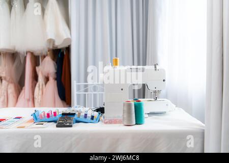 Machine à coudre et accessoires sur la table pour le travail d'un tailleur de robe de mariée Banque D'Images