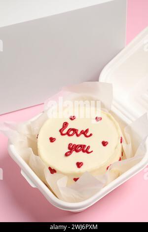 Gâteau bento savoureux avec inscription Love You dans une boîte à emporter sur une table rose Banque D'Images