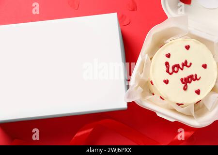 Savoureux gâteau bento avec Love You inscription dans un emballage à emporter et boîte sur table rouge, pose à plat Banque D'Images