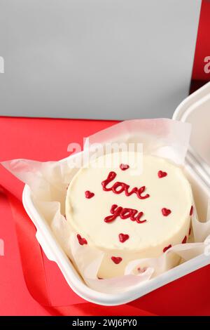Savoureux gâteau bento avec Love You inscription dans un emballage à emporter sur table rouge, gros plan Banque D'Images