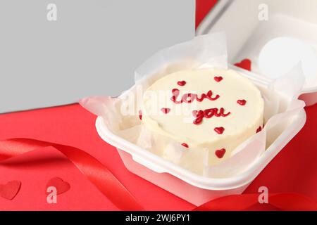 Savoureux gâteau bento avec Love You inscription dans un emballage à emporter sur table rouge, gros plan. Espace pour le texte Banque D'Images