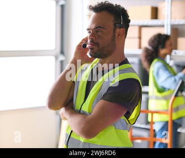 Homme atteint du syndrome de Down travaillant dans un entrepôt portant un casque Banque D'Images