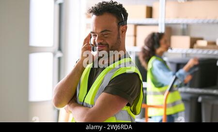 Homme atteint du syndrome de Down travaillant dans un entrepôt portant un casque Banque D'Images