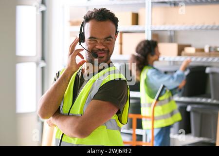 Homme atteint du syndrome de Down travaillant dans un entrepôt portant un casque Banque D'Images