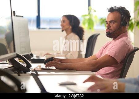 Homme atteint du syndrome de Down portant un micro-casque travaillant dans l'équipe du centre d'appels du bureau Banque D'Images