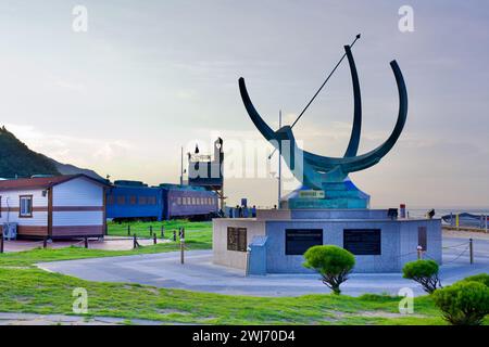 Gangneung City, Corée du Sud - 29 juillet 2019 : Jeongdongjin Hourglass Park présente une sculpture de cadran solaire au premier plan avec des trains sur les rails Banque D'Images