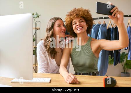 Deux femmes amis courir en ligne Fashion Business de la maison posant pour Selfie sur téléphone portable Banque D'Images